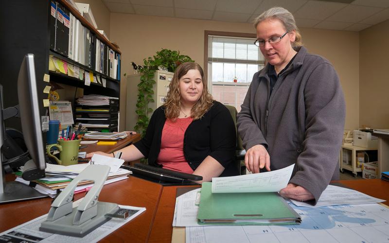 Two producers reviewing financial paperwork in a farm office.
