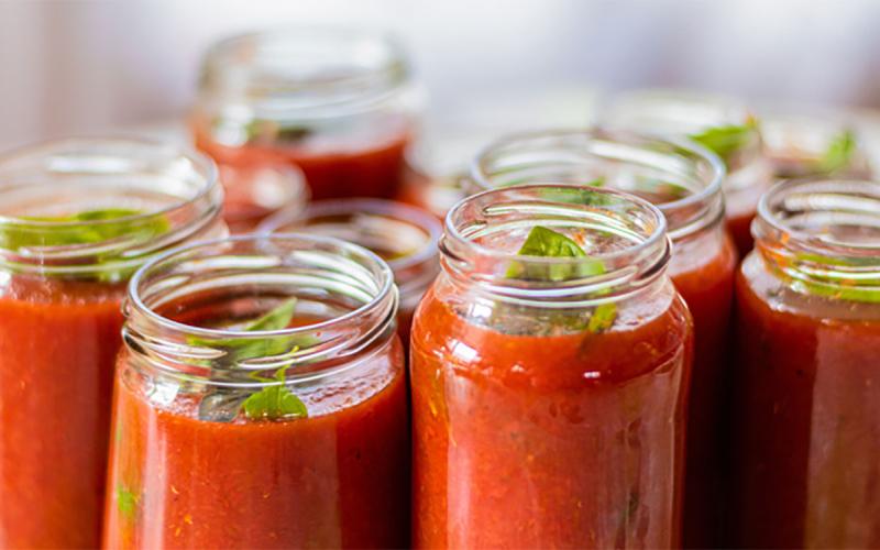 Several canning jars filled with tomato sauce and herbs.