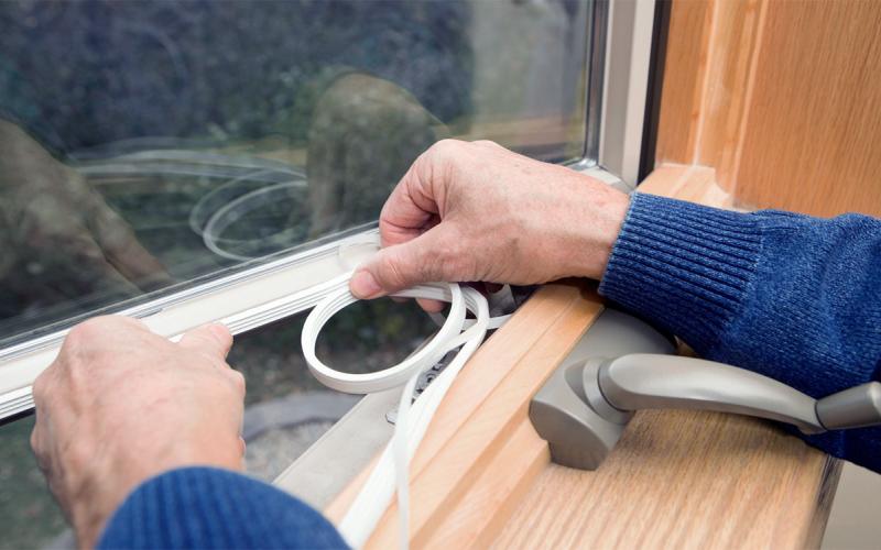 Installing weather stripping around a window.
