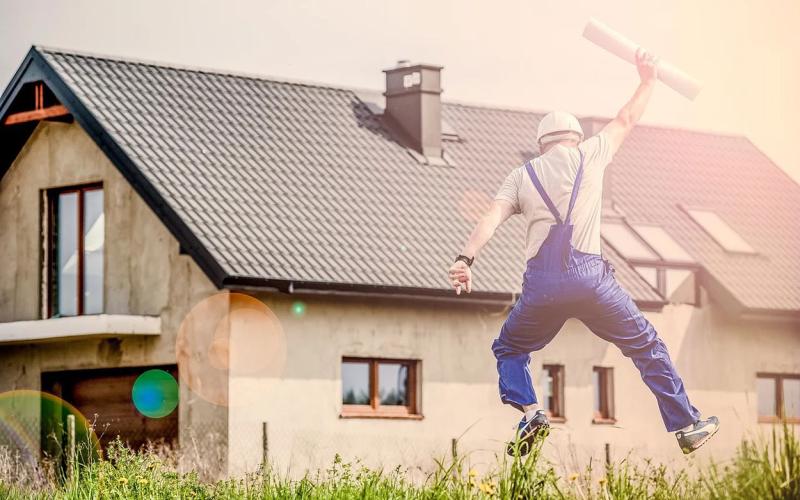 Architect leaping in front of a home.