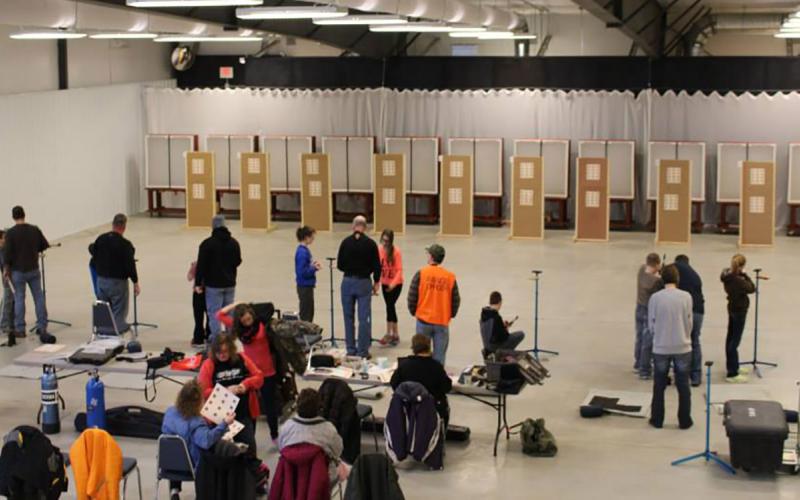Shooting sports instructors and participants training at an indoor range.