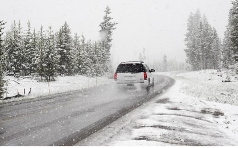 SUV driving on a snow and tree lined road