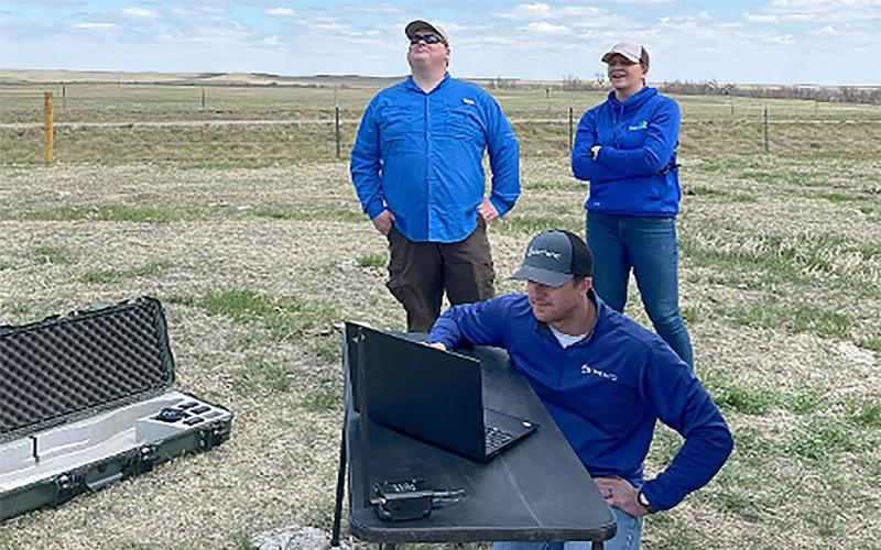 People standing in field observing a drone flight.