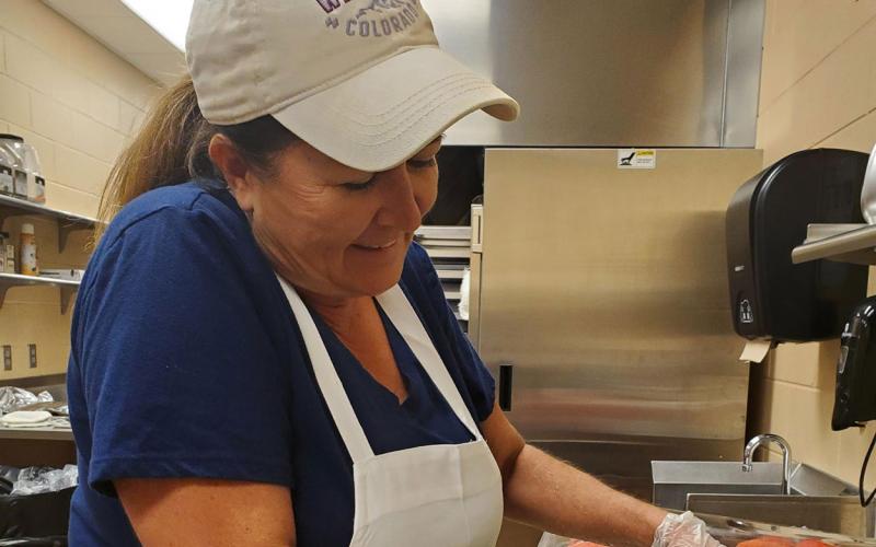 Dawn Johnson preparing watermelon in a school kitchen.