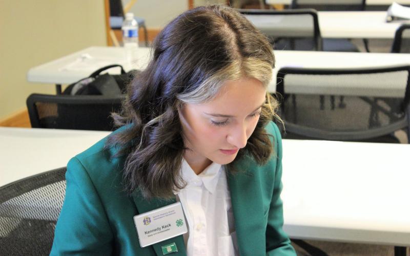 State 4-H Ambassador sitting at a table filling out an application