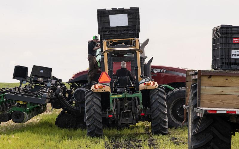 Two producers inspecting a soybean planter.
