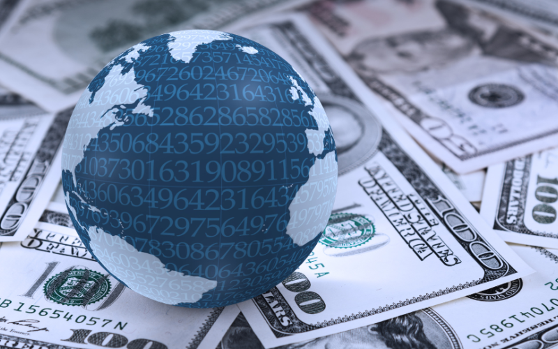 A globe sitting on many 100 dollar bills