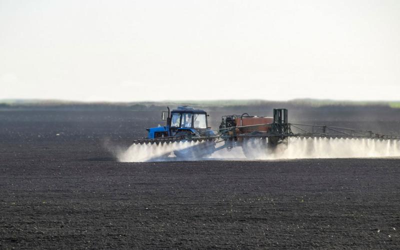 Tractor applying preemergence herbicide on a freshly planted field.