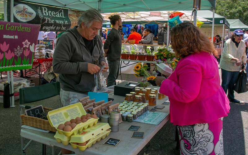 Vendor selling a variety of food products at a farmer’s market.