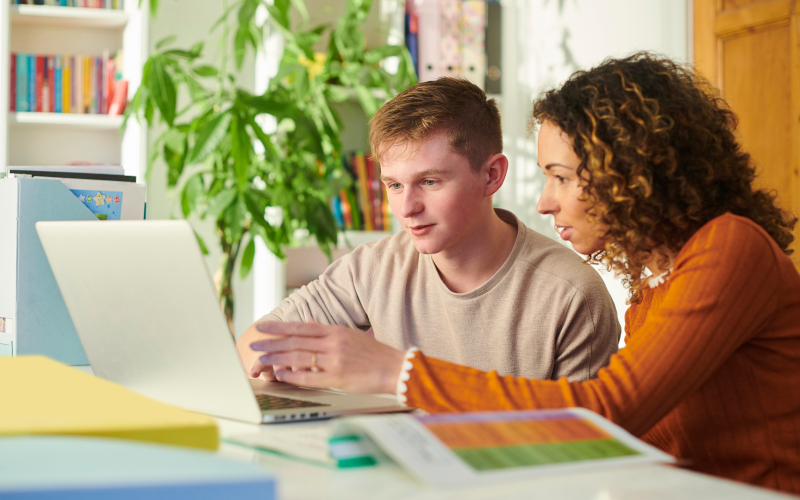 Woman helping boy on computer