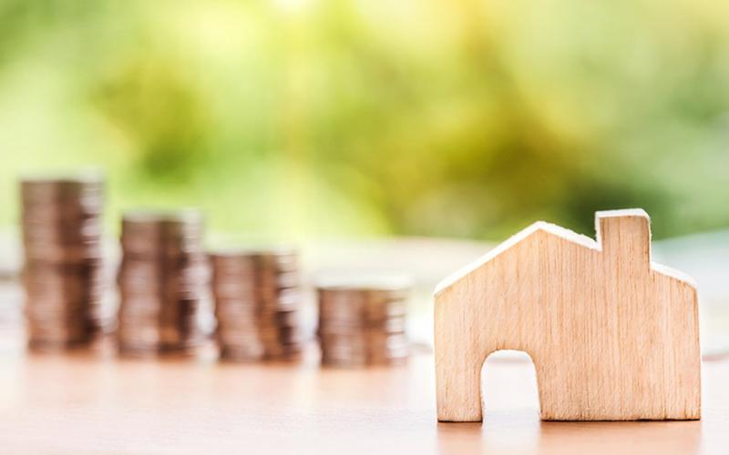 Wooden house with stacks of coins in the background.