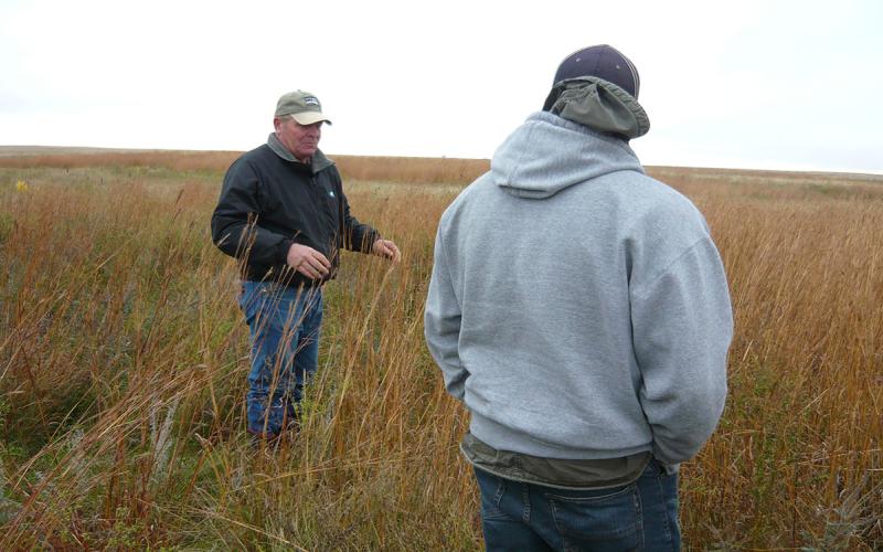 Two men standing in a pasture.