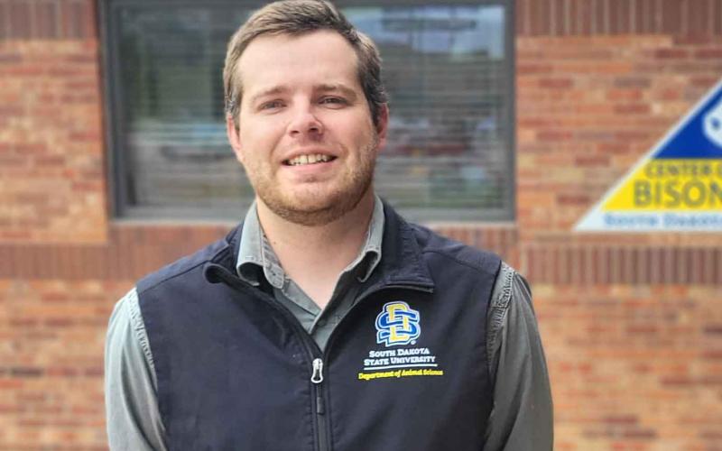 Logan Vandermark stands outside in front of a brick building