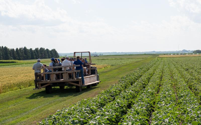 A group of people rides on a trailer through the Northeast Research Farm