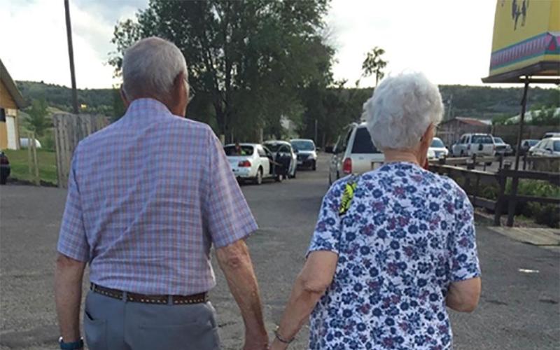 Two older adults holding hands while walking.