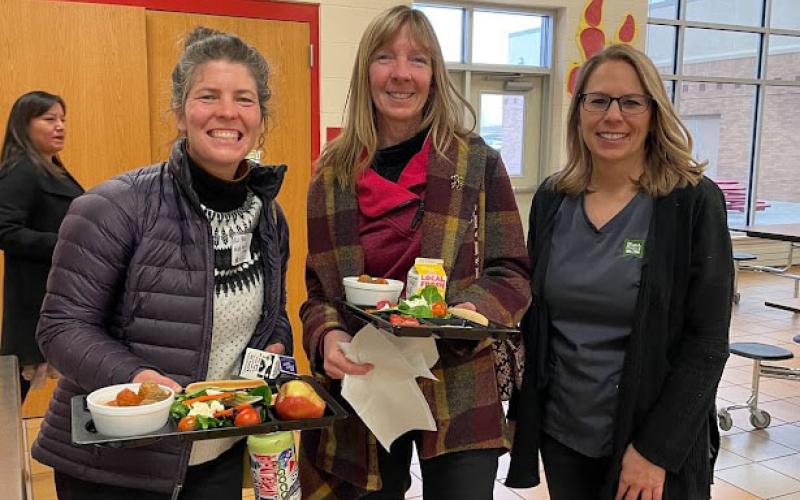 Three ladies standing with lunch trays of food