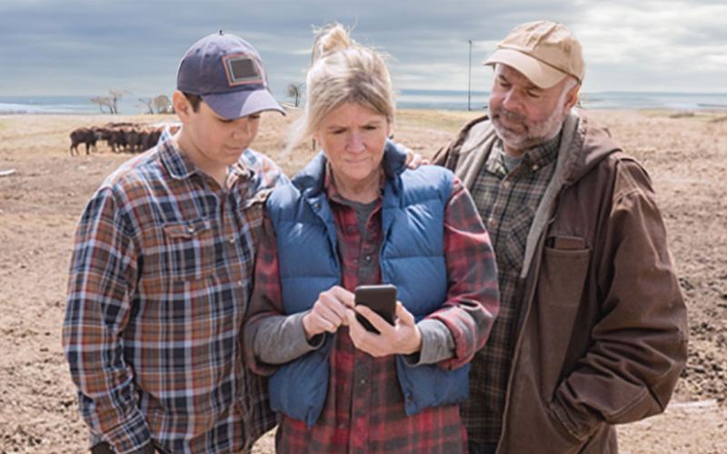 Ranch family examining data on a smart phone.