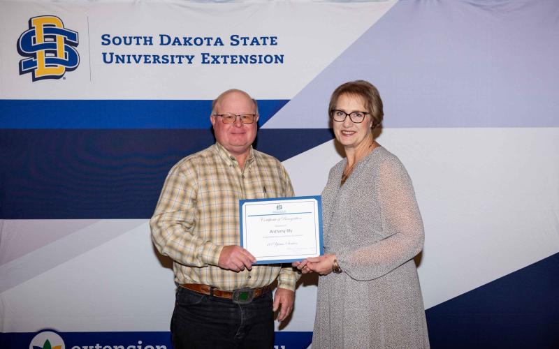 Anthony Bly receives a certificate for 10 years of service from SDSU Extension Director Karla Trautman