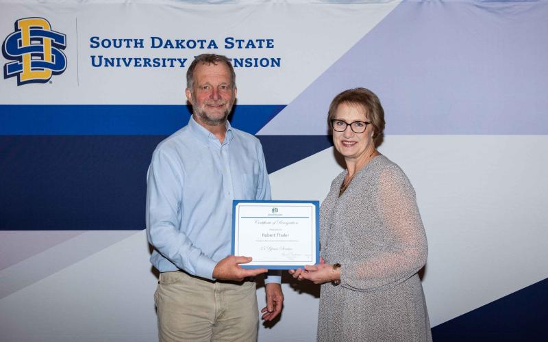 Bob Thaler smiles as he receives his certificate for 35 years with SDSU from Karla Trautman