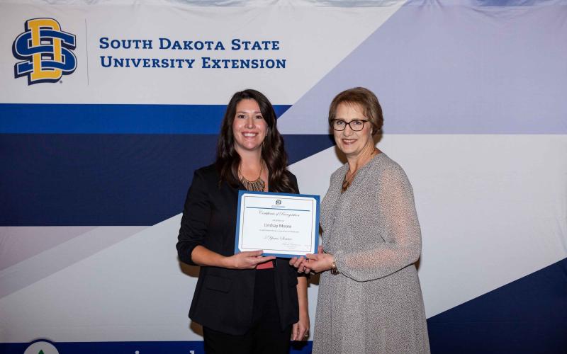 Lindsay Moore receives a certificate for 5 years of service from Karla Trautman