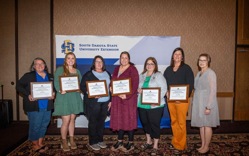 SDSU Extension professionals smile at the camera displaying their Excellence in Virtual Program Delivery Award certificates