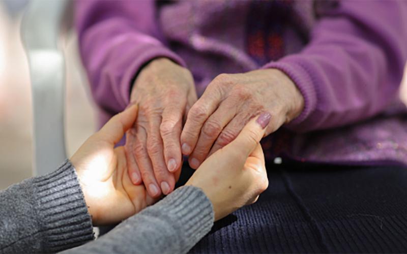 Young woman holding an older woman’s hands.