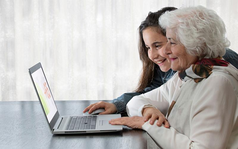 Granddaughter reviewing information on a laptop with her grandmother.
