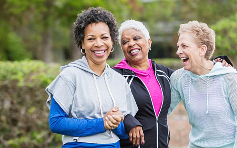 Three older women going for a walk near a park.
