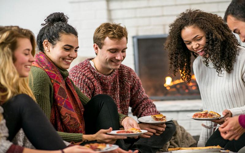 Group of friends enjoying pie by the fireside at a Christmas gathering.