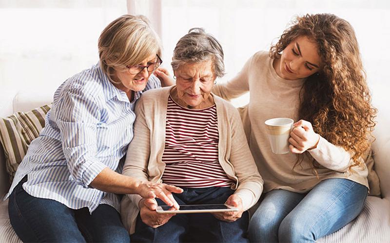 Mother and daughter reviewing information on a tablet with grandmother.
