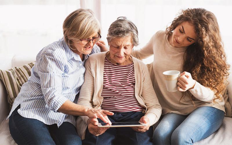 Mother and daughter reviewing information on a tablet with grandmother.