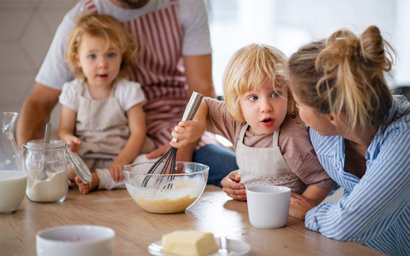 Mother and father giving two young children a cooking lesson.
