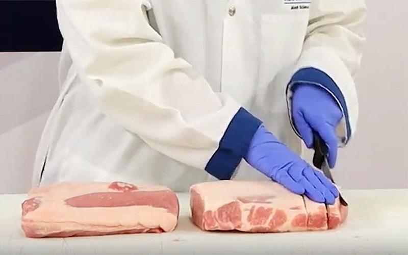 Two pork loins on a butcher counter. One is being cut into quarter-inch pork chops.