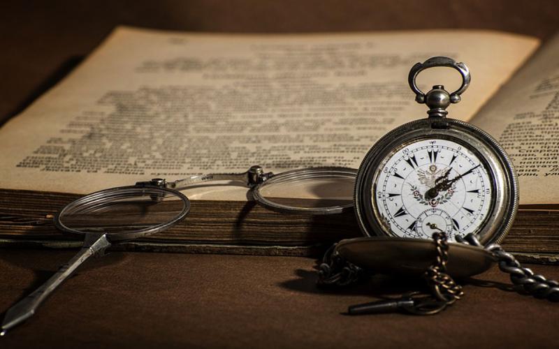 Glasses and pocket watch beside an open journal.