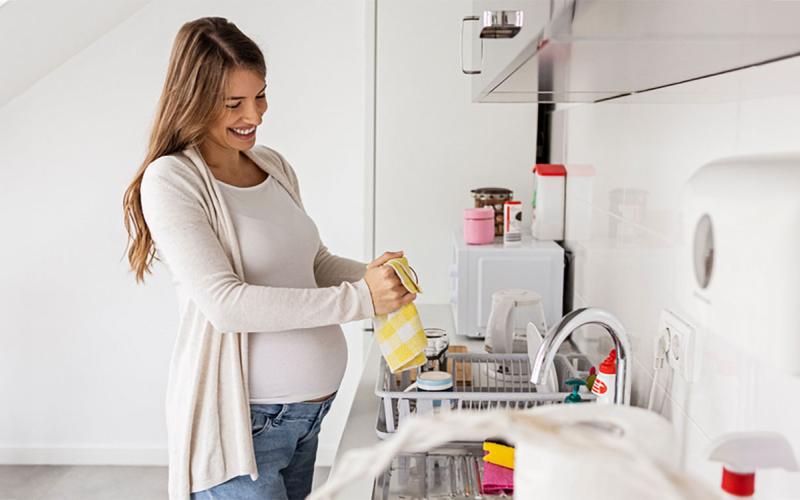 Pregnant mother drying her hands after washing them at the kitchen sink.