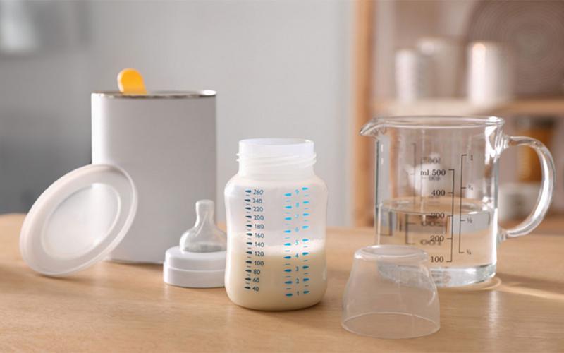 Infant formula, bottle, distilled water, and can of formula on a kitchen counter.