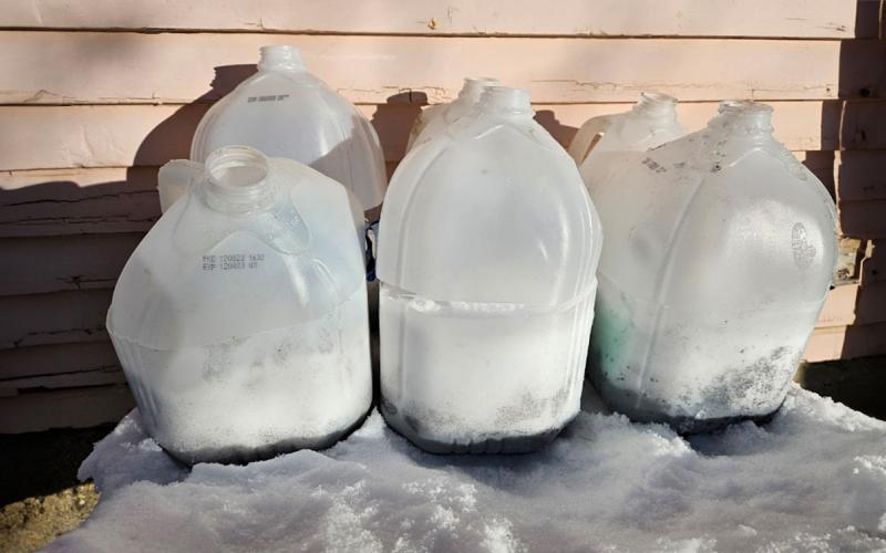 Jugs lined up outside with snow inside.