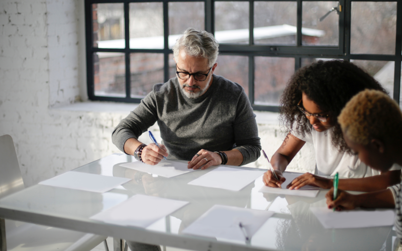 Three people sitting around a table writing