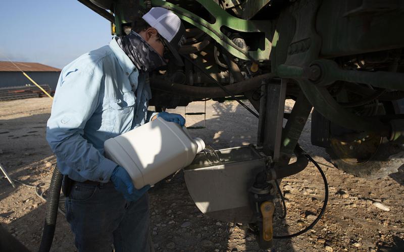 Producer loading pesticide into a sprayer tank.