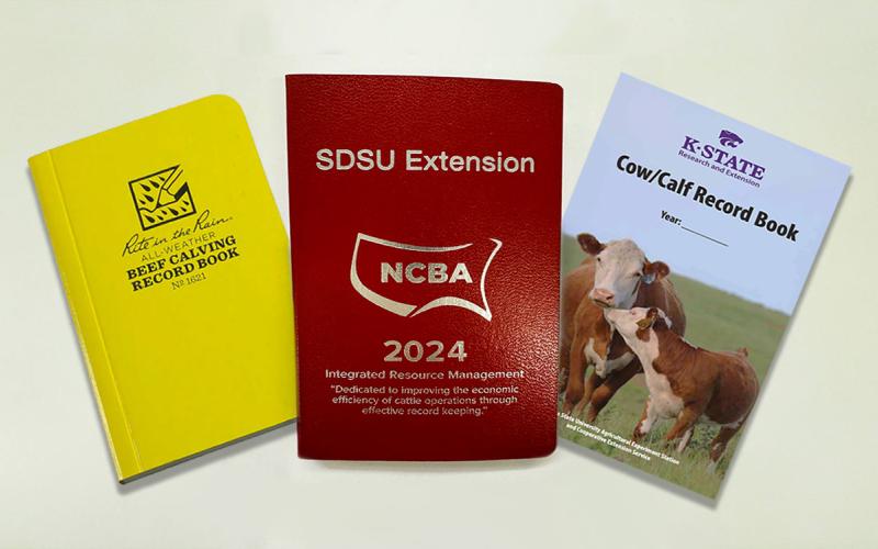 Three calving books on display: Rite in the Rain book, SDSU Extension IRM Redbook, and the K-State cow/calf record book.