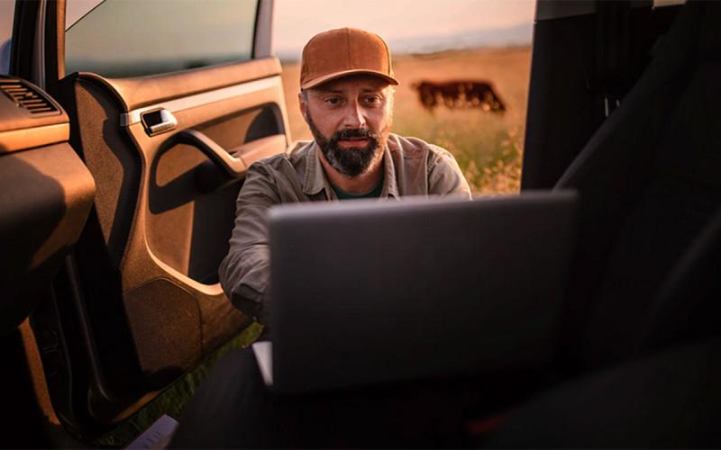 Rancher viewing data on a laptop on the seat of his truck.