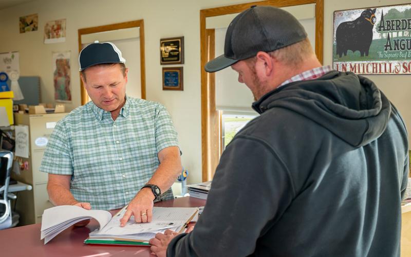 Two ranchers reviewing a checklist in a farm office.
