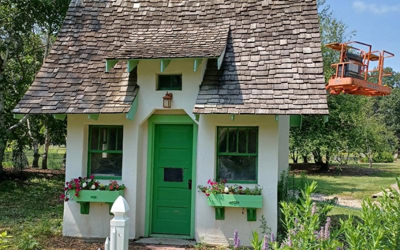 a small cottage with a green door and weathered shingles