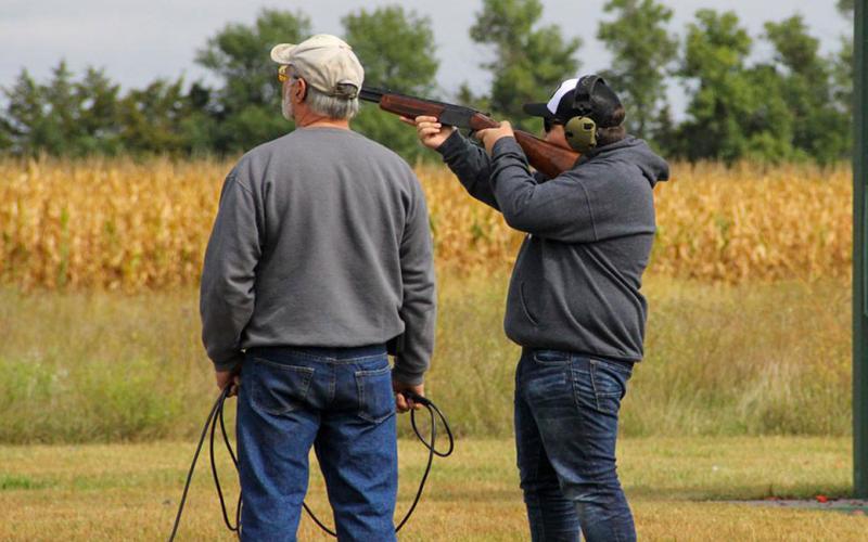 4-H shooting sports coach and youth at a trap shooting range.