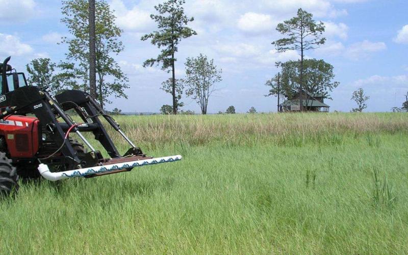 Tractor-mounted wick applicator applying herbicide to a pasture.