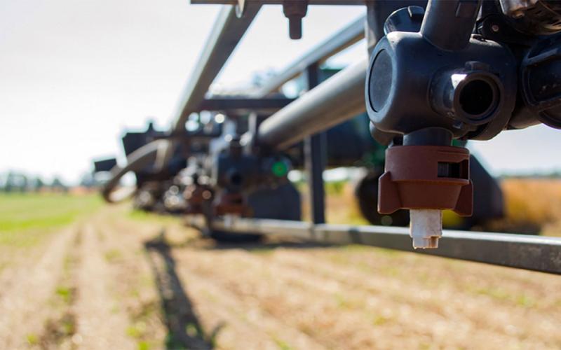 Nozzle on a boom sprayer in a crop field.
