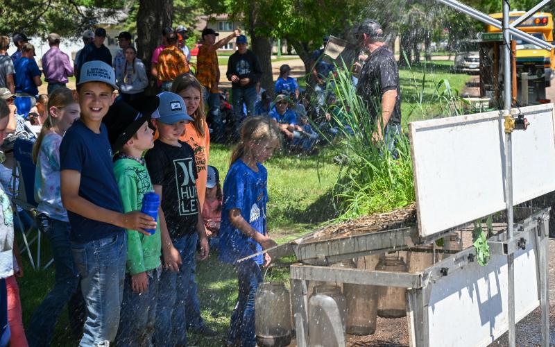 A group of children stands in front of a display with plants and simulated rainfall