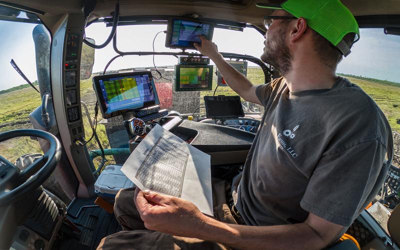 Producer analyzing data on a series of screens inside a tractor equipped for precision agriculture.