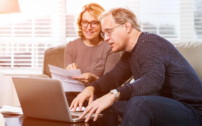 Couple reviewing social security forms and information at a laptop computer.