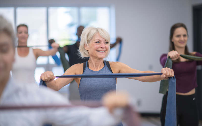older adult in a work out class using a resistance band.
